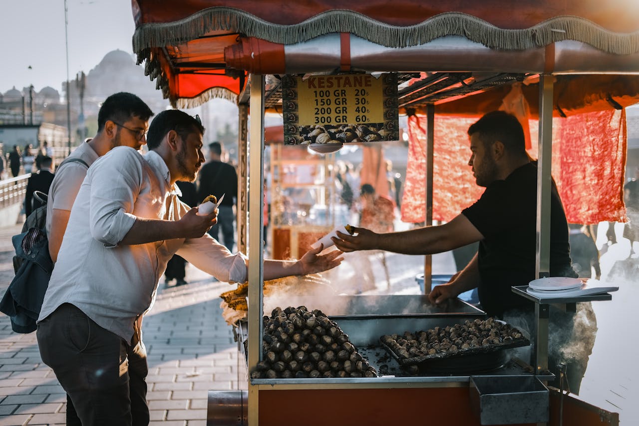 A bustling street market scene with people buying roasted chestnuts in İstanbul.